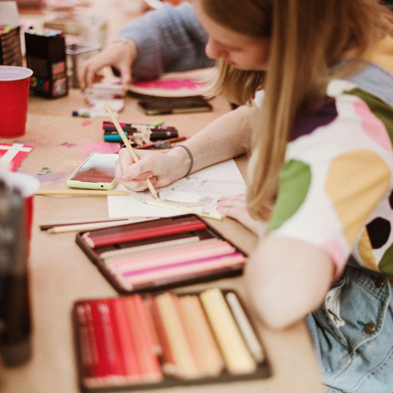 a young person uses colored pencils to draw an image.